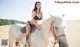 A woman in a bikini riding a white horse.