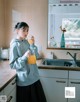 A woman standing in a kitchen holding a glass of orange juice.