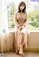 A woman sitting on a window sill in a dress.