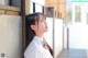 A woman in a white shirt leaning against a wall.