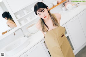 A woman standing in front of a sink in a kitchen.