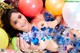 A woman laying on top of a pile of balloons.