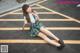 A woman in a school uniform sitting on the ground.