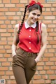 A woman in a red shirt and brown pants posing for a picture.