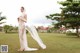 A woman in a wedding dress standing in the grass.