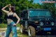 A woman standing in front of a black jeep.